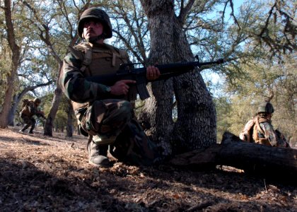 US Navy 071106-N-0775Y-132 Lt. Brian Foster checks his flank as his patrol moves forward during an officer's field training exercise on board Fort Hunter Liggett