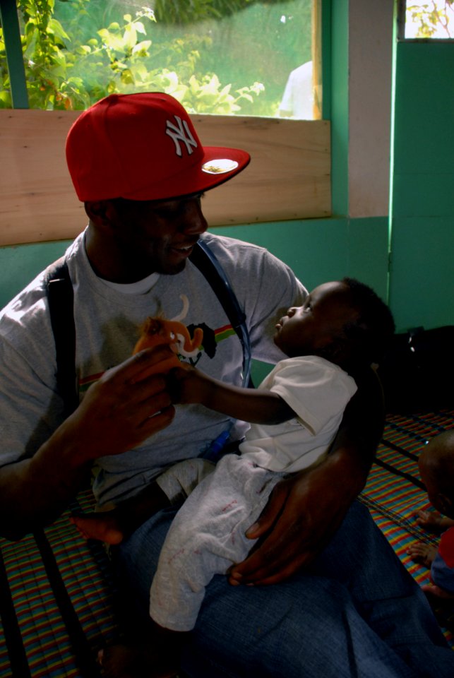 US Navy 071108-N-0193M-083 Africa Partnership Station (APS) volunteer, Electrician's Mate 3rd Class Jermario Gordon, plays with an infant at La Pouponniere, an orphanage where APS volunteers spent the day building walls, laying