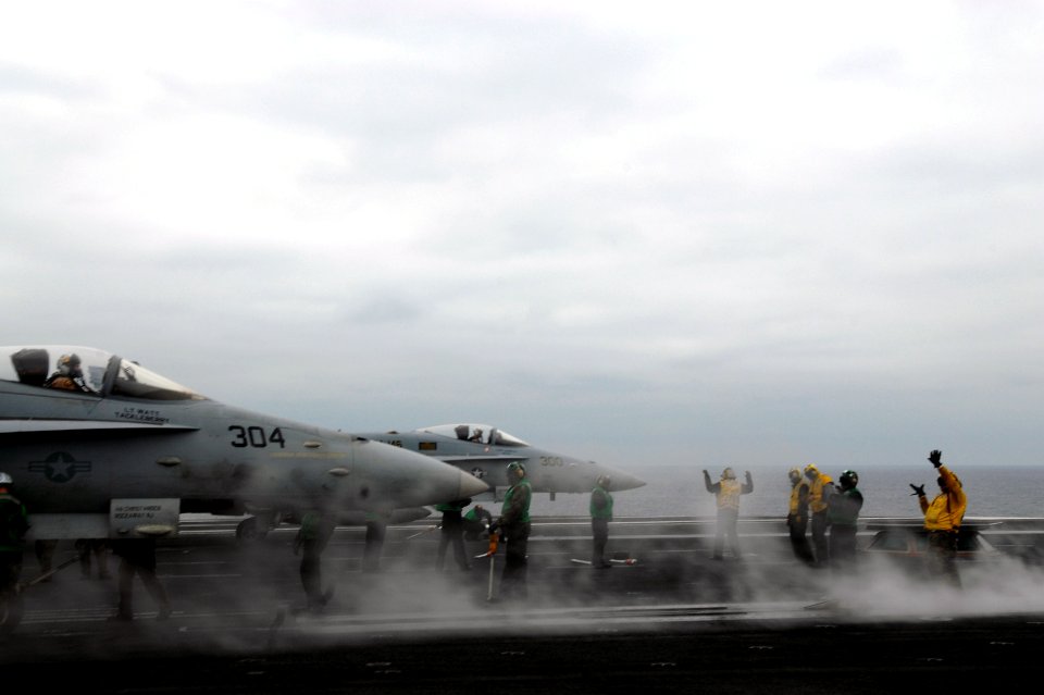 US Navy 071108-N-0555B-070 Aircraft directors, wearing yellow flight deck uniforms, signal two F-A-18C Hornets, attached to the Blue Diamonds of Strike Fighter Squadron (VFA) 146
