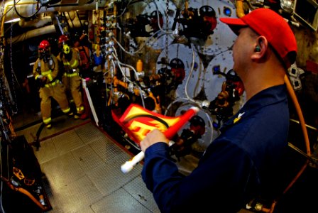 US Navy 071110-N-7883G-037 Machinery Repairman 1st Class Regibert Agustino waves a flag used to simulate a fuel fire during a main machinery space fire drill aboard USS Kitty Hawk (CV 63)