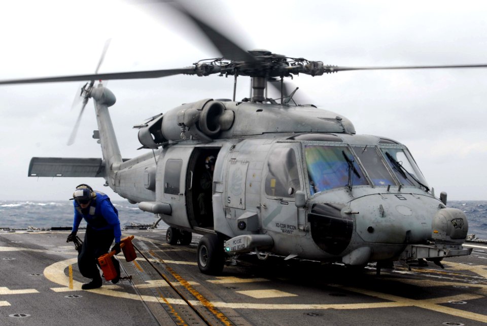 US Navy 071121-N-3136P-063 A boatswain's mate removes the chock and chains from an SH-60F Seahawk, from Helicopter Anti-submarine Squadron (HS) 14, before taking off from the flight deck of guided-missile destroyer USS Mustin (