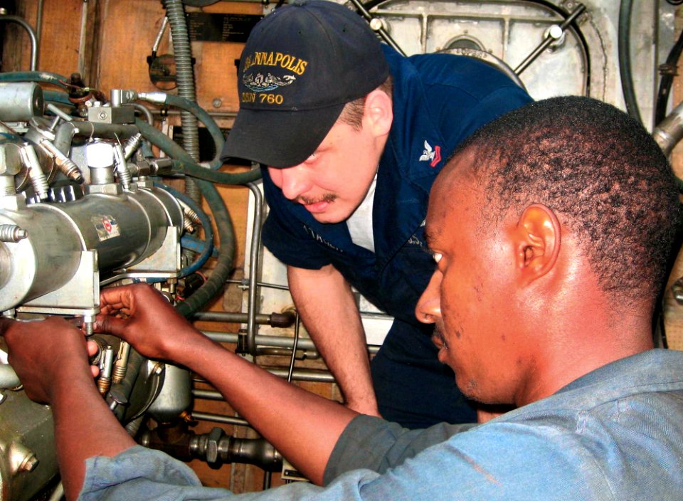 US Navy 071116-N-0000X-001 Machinist's Mate 2nd Class Luke Vontagen, a diesel technician assigned to USS Annapolis (SSN 760), works with a Cape Verdean Coast Guardsman to repair a propulsion engine