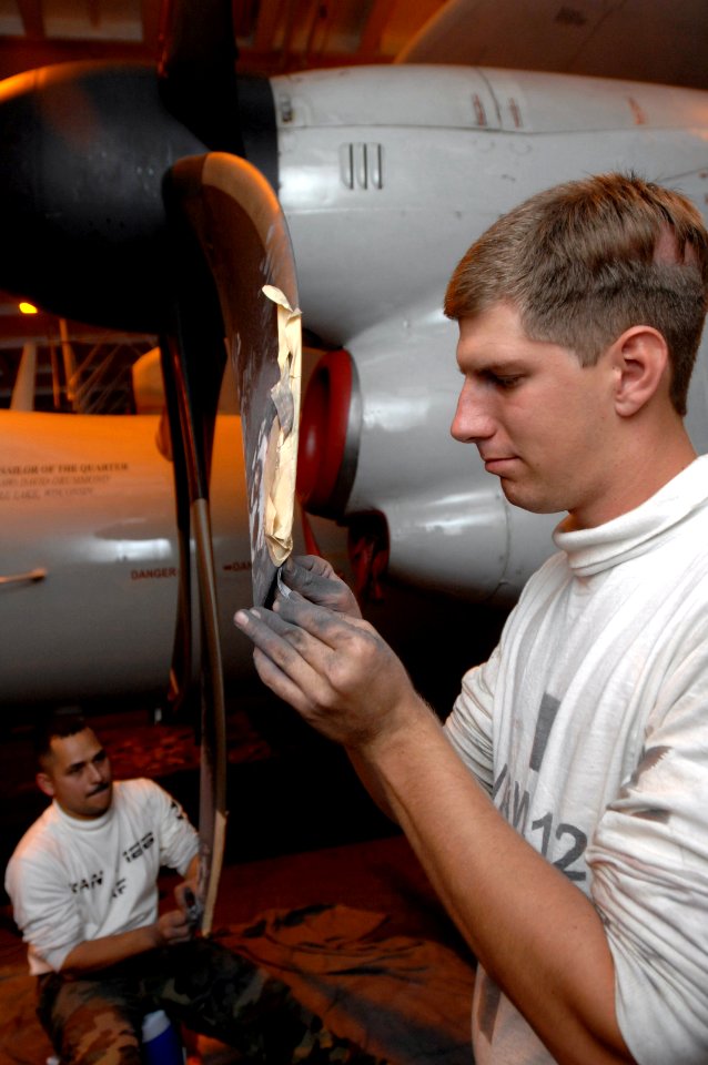 US Navy 071126-N-0455L-005 Sailors stationed aboard the Nimitz-class aircraft carrier USS Harry S. Truman (CVN 75), remove paint from the propeller of an E-2C Hawkeye