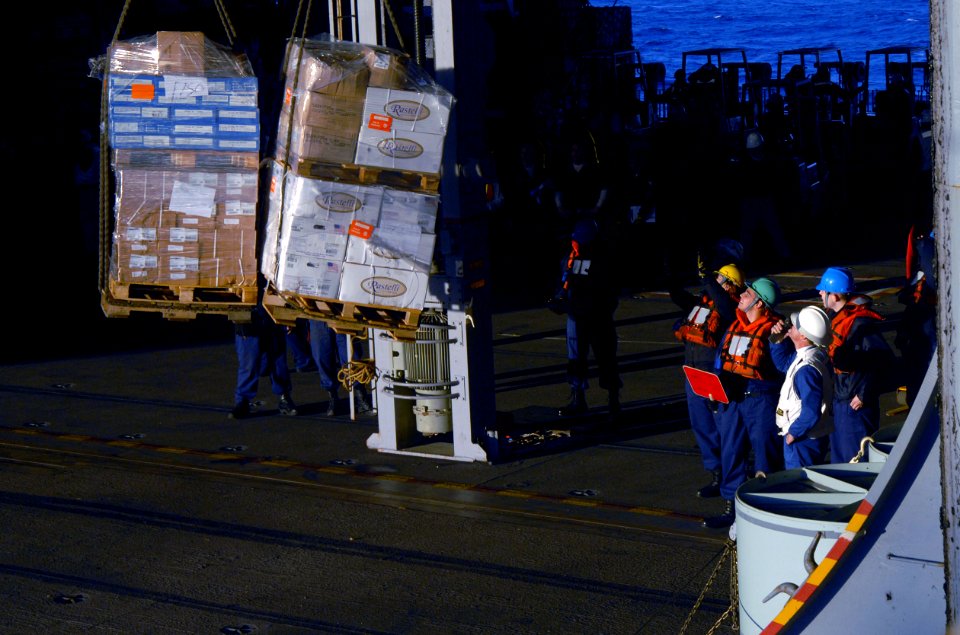 US Navy 071118-N-1688B-079 Sailors receive stores in the hangar bay of the Nimitz-class nuclear-powered aircraft carrier USS Harry S. Truman (CVN 75) during a replenishment-at-sea