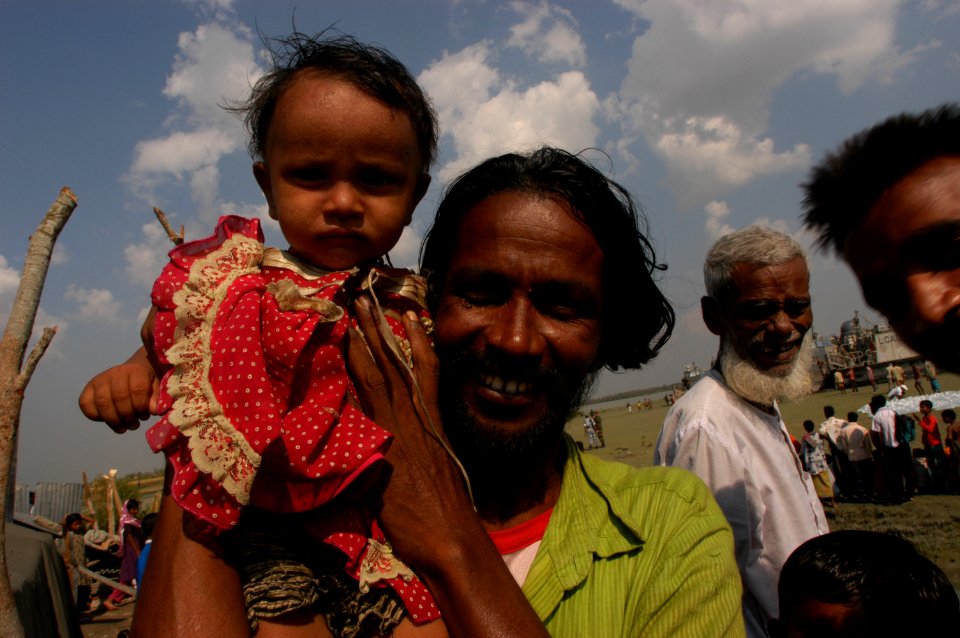US Navy 071128-N-5642P-122 A man holds his daughter up for a photograph in the devastated village