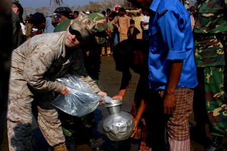 US Navy 071128-N-5642P-013 U.S. Marine Corporal Gennaro Carbone, assigned to the 22nd Marine Expeditionary Unit (Special Operations Capable) distributes water to the local residents photo