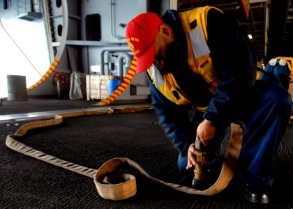 US Navy 071120-N-9898L-025 Damage Controlman 3rd Class Reginald Rose attaches a veri-nozzle to a fire hose in order to conduct a test of a P-100 water pump in the hangar bay aboard the Nimitz-class nuclear-powered aircraft carr