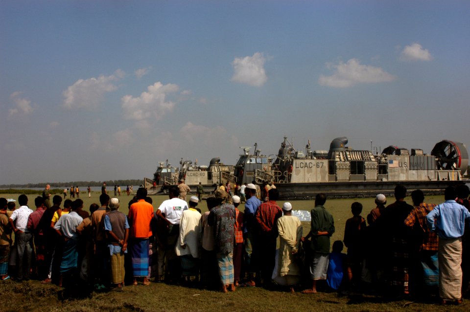 US Navy 071128-N-5642P-081 People gather along a stream bed to watch bags of water being unloaded from two landing craft air cushions (LCAC) assigned to Assault Craft Unit (ACU) 4