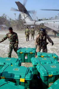 US Navy 071128-N-7955L-019 A Bangladesh Army solider and a Marine Corps aircrew chief unload containers of supplies from the CH-53E Sea Stallion helicopter which is attached to Marine Medium Helicopter Squadron (HMM) 261
