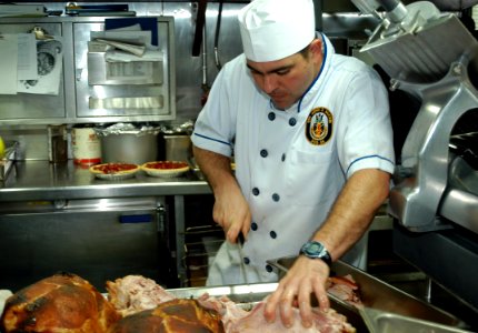 US Navy 071123-N-9123L-001 Culinary Specialist 1st Class Matthew McFarlane slices ham for the Thanksgiving Day meal aboard the guided-missile destroyer USS John S. McCain (DDG 56)
