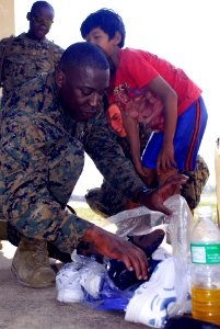 US Navy 071128-N-4010S-286 Maj. Jeramy Green searches through a bag of donated shoes for a young Cambodian boy