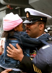 US Navy 071127-N-0483B-006 Chief Aviation Electronics Technician (SW-AW) Gerald William holds his daughter during a homecoming ceremony for the aircraft carrier USS Kitty Hawk (CV 63), shortly after the ship arrived at Commande