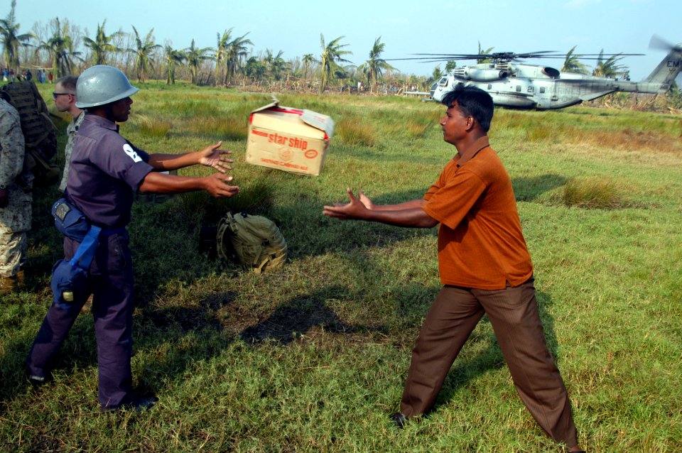 US Navy 071128-N-7955L-110 A Bangladesh military member passes a box of blankets to a local resident