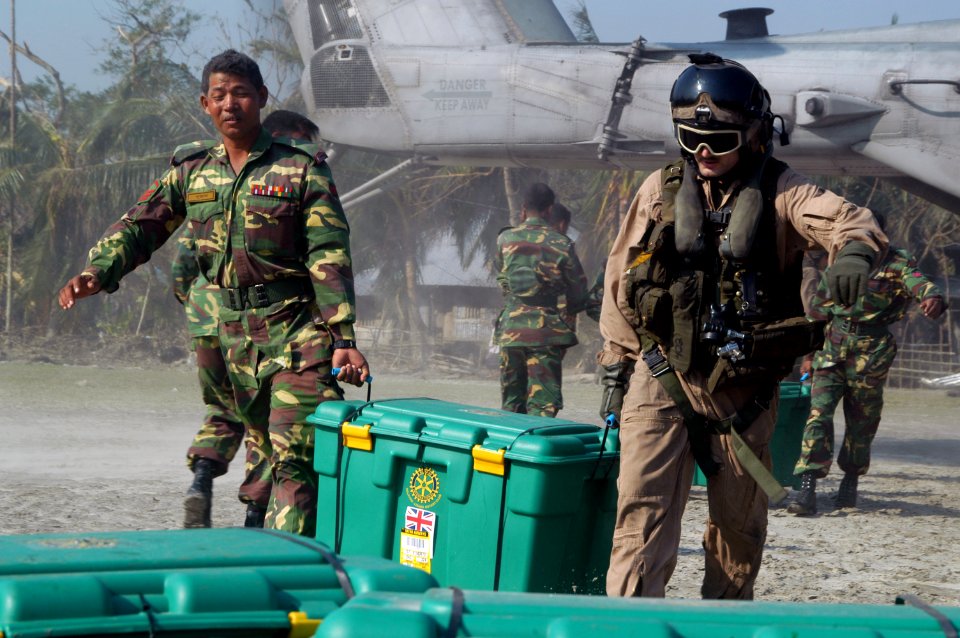 US Navy 071128-N-7955L-021 A Bangladesh Army solider and a Marine Corps aircrew chief unload containers of supplies from the CH-53E Sea Stallion helicopter attached to Marine Medium Helicopter Squadron (HMM) 261