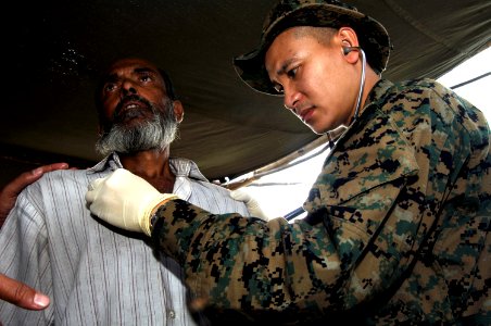 US Navy 071204-N-2420K-018 Lt. Cmdr. Lu Le, a Navy surgical doctor attached to 11th Marine Expeditionary Unit Special Operations Capable (SOC), uses a stethoscope to examine a Bangladeshi fisherman photo