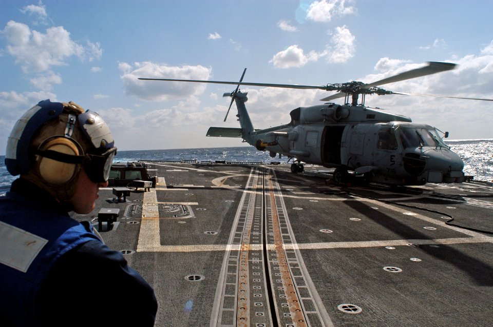 US Navy 071205-N-9123L-001 A Sailor aboard the guided missile destroyer USS McCampbell (DDG 85) stands by as a SH-60B helicopter prepares to lift off