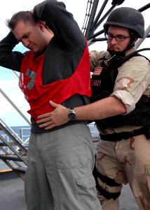 US Navy 071202-N-2838W-143 A member of the guided-missile destroyer USS Bulkeley's (DDG 84) visit, boarding, search and seizure team searches one of the acting suspect crewsman during their simulation boarding aboard the traini photo