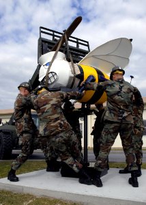 US Navy 071204-N-1120L-023 Seabees assigned to Naval Mobile Construction Battalion (NMCB) 7 work together to place a Bee in front of the Headquarters building on Camp Shields