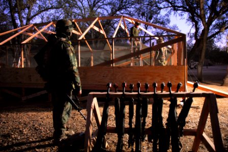 US Navy 071201-N-0775Y-076 Builder 1st Class Bruce Beebe attached to Naval Mobile Construction Battalion (NMCB) 3, keeps a weapons watch as he observes Seabees build a tent while illuminated with a light