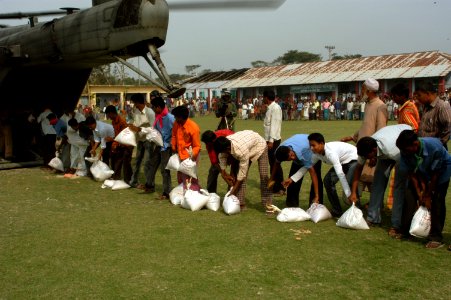 US Navy 071203-N-5642P-269 Local residents assist in unloading boxes food from a CH-53E Super Stallion helicopter, attached to Marine Medium Helicopter Squadron (HMM) 261 photo