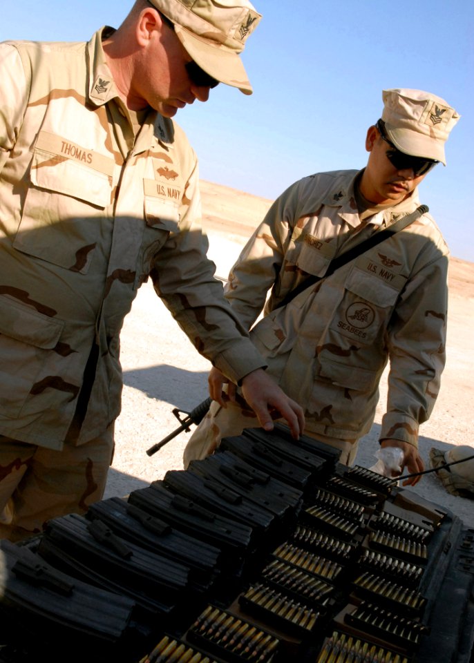 US Navy 071209-N-3857R-009 Storekeeper 1st Class Joseph Sanchez and Builder 1st Class Billy Thomas, both attached to Naval Mobile Construction Battalion (NMCB) 1, lay out ammunition prior to weapons familiarization training