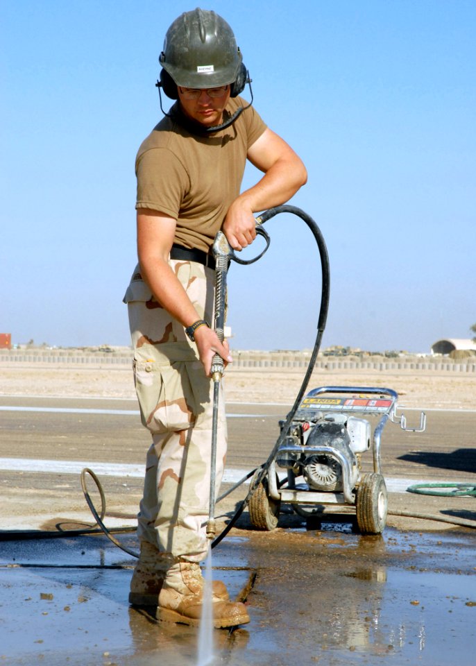 US Navy 071210-N-3857R-001 Engineering Aide Constructionman Devin Ahearn, of Naval Mobile Construction Battalion (NMCB) 1, uses a pressure washer to clean out the grooves of a pad of freshly placed concrete on a runway at Camp