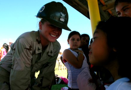US Navy 071218-N-7367K-005 Builder 3rd Class Taylor Crow, a Seabee attached to Mobile Construction Battalion (NMCB) 1, Guam Det., shares a moment with a student at Chief Brodie Memorial Elementary School