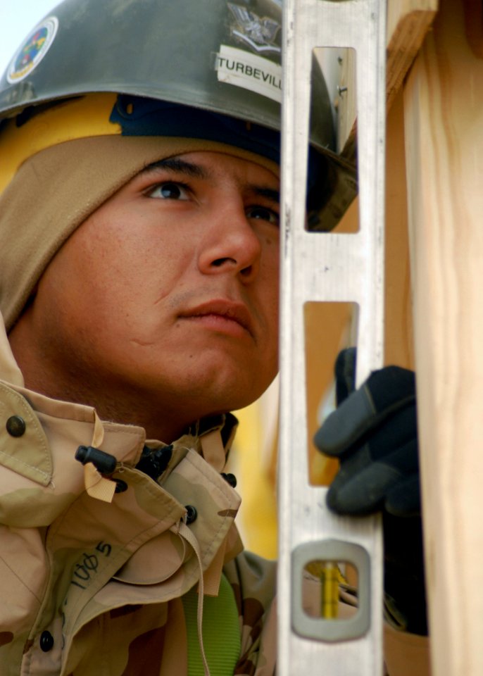 US Navy 071221-N-3857R-009 Builder 3rd Class Adam Turbeville, assigned to Naval Mobile Construction Battalion (NMCB) 1, checks the level on a truss while working on the construction of a fellowship hall at Camp Ramadi