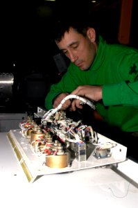 US Navy 071219-N-5033P-040 Aviation Support Equipment Technician 2nd Class Rob Gilman traces wires on a mobile electric power plant in the Hangar Bay of the amphibious assault ship USS Kearsarge (LHD 3)