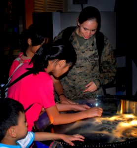 US Navy 071218-N-4774B-479 U.S. Marine Sgt. Marilyn Zeledon, network administrator for the 11th Marine Expeditionary Unit (MEU), shows some children from Singapore an exhibit on liquid nitrogen at the Singapore Science Museum