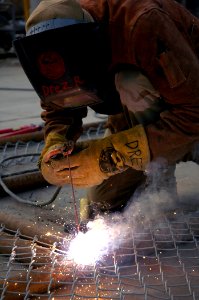 US Navy 080105-N-7367K-001 A Seabee assigned to Naval Mobile Construction Battalion (NMCB) 15, cuts a piece of pipe for a fence