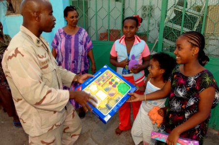 US Navy 071218-N-3931M-019 U.S. Navy Hospital Corpsman 1st Class Ronie Thompson, from Combined Joint Task Force-Horn of Africa (CJTF-HOA), presents a gift to a local resident during a toy distribution project