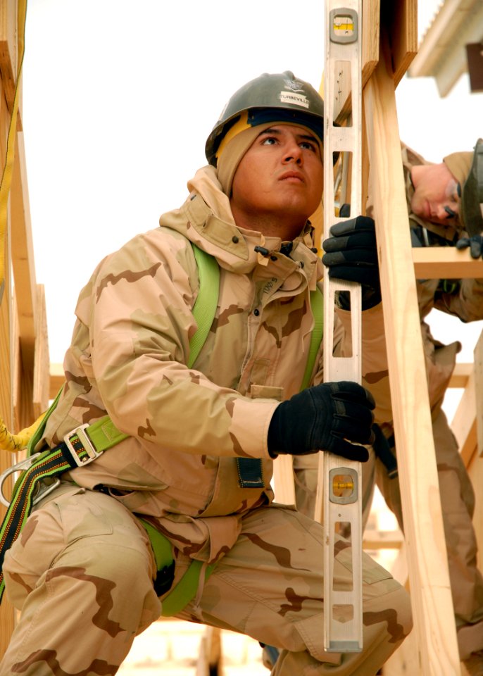 US Navy 071221-N-3857R-008 Builder 3rd Class Adam Turbeville, assigned to Naval Mobile Construction Battalion (NMCB) 1, checks the level on a truss while working on the construction of a fellowship hall