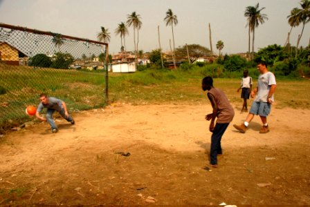 US Navy 071227-N-0193M-714 Operations Specialist Seaman Cody Thompson dives to block a soccer ball while playing with Construction Mechanic 1st Class Eric Dickinson and local children in Takoradi, Ghana