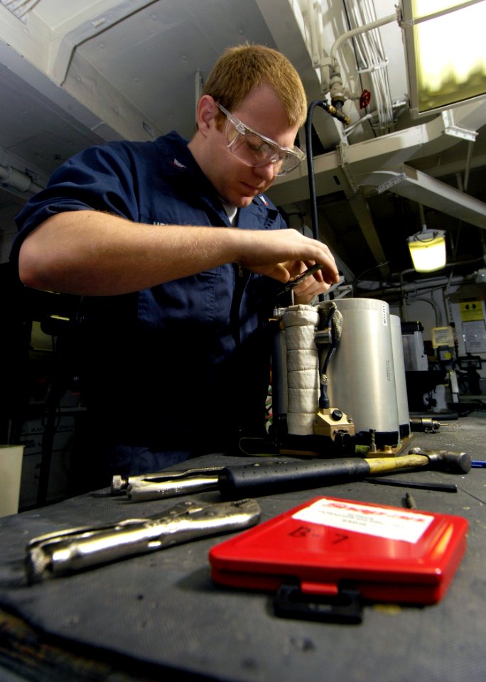 US Navy 080107-N-2880M-007 Aviation Structural Mechanic 3rd Class Jeffery Hendricks removes a screw from an Onboard Oxygen Generating System (OBOGS)