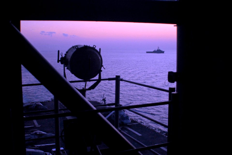 US Navy 071229-N-4774B-014 The amphibious dock landing ship USS Germantown (LSD 42), in the distance, passes the amphibious assault ship USS Tarawa (LHA 1) as dawn breaks