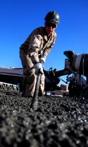 US Navy 080107-N-7367K-005 Builder 3rd Class Justin Odonnell, assigned to Naval Mobile Construction Battalion (NMCB) 1, Task Force Sierra, uses a rake to help level out freshly poured concrete photo