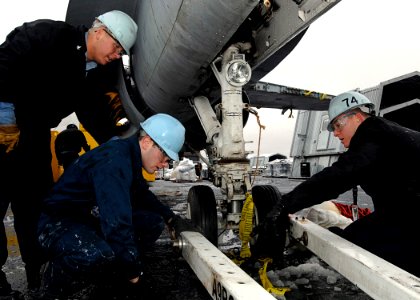 US Navy 080108-N-4954I-021 Three aviation boatswain's mates attach a tow bar to the nose wheel of an F-A-18C Hornet training aircraft on the flight deck of USS John C. Stennis (CVN 74)