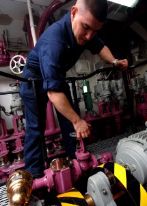 US Navy 080106-N-8923M-006 Aviation Boatswain's Mate Fuel 3rd Class Matthew L. Fox opens a JP-5 fuel tank releasing free water from a storage tank in pump room 3