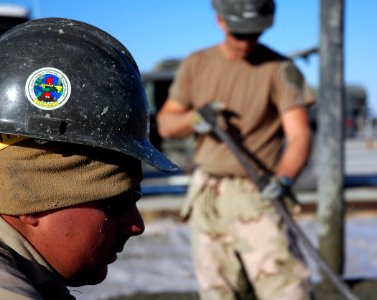US Navy 080107-N-7367K-007 Builder 3rd Class Shawn Laborde, assigned to Naval Mobile Construction Battalion (NMCB) 1, Task Force Sierra, looks on while other Seabees continue laying concrete photo