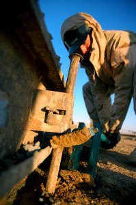 US Navy 080107-N-7367K-001 Builder 3rd Class Ryan Richards, assigned to Naval Mobile Construction Battalion (NMCB) 1, Task Force Sierra, uses a stake puller to help remove the forms around a newly hardened concrete pad photo