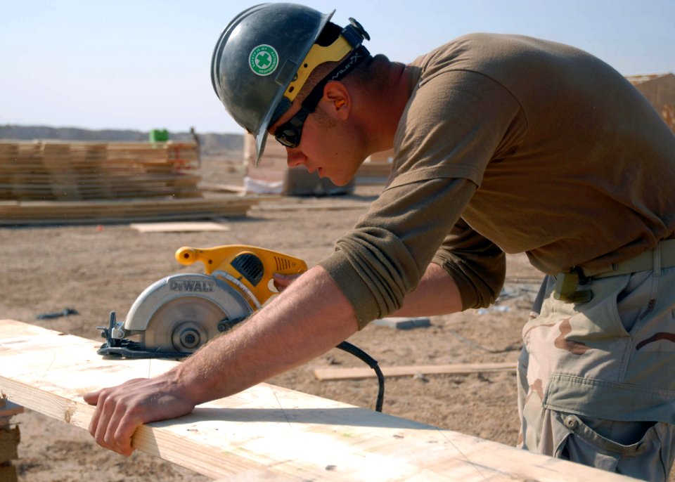 US Navy 080104-N-3857R-006 Steelworker 2nd Class James Branstietter assigned to Naval Mobile Construction Battalion (NMCB) 1, makes a cut on a piece of lumber during the construction of a combat outpost that will be used by the