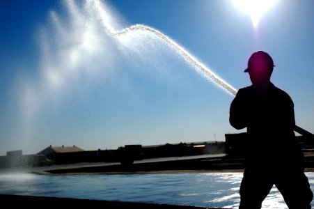 US Navy 080107-N-7367K-008 A Seabee assigned to Naval Mobile Construction Battalion (NMCB) 1, Task Force Sierra, waters a freshly laid pad of concrete to aid the curing process