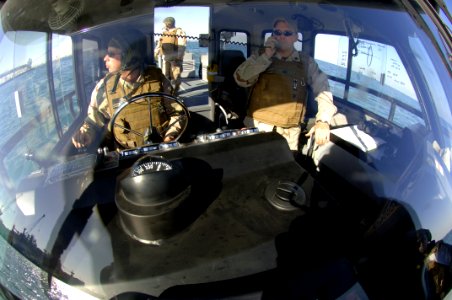 US Navy 080108-N-7027P-017 Engineman 2nd Class Shawn Bills, left, and Master-At-Arms 1st Class Sean Cox, both assigned to NCWRON- 21, look for suspicious contacts in the water as their unit provides security for the departing d photo