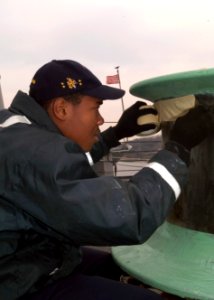 US Navy 080109-N-9520G-001 Seaman Cornelues Michell, assigned to deck department aboard the Arleigh Burke-class guided-missile destroyer USS John S. McCain (DDG 56), masks off a section of a capstan to be painted