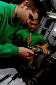 US Navy 080110-N-0455L-002 Aircrew Survival Equipmentman 2nd Class Graciano Lupercio and Aircrew Survival Equipmentman Airman Cliford Manera rewire a failed part on an Onboard Oxygen Generating System (OBOGS) compressor
