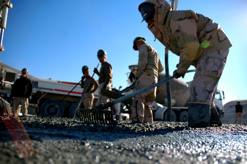 US Navy 080107-N-7367K-003 Builder 3rd Class Ryan Richards, assigned to Naval Mobile Construction Battalion (NMCB) 1, Task Force Sierra, uses a rake to help level out freshly poured concrete