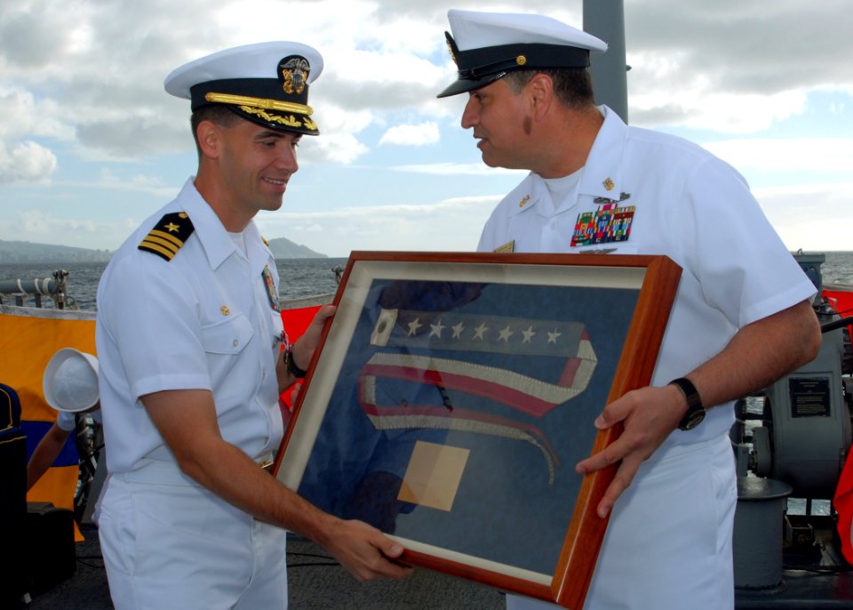 US Navy 080114-N-5476H-076 Arleigh Burke-class guided-missile destroyer USS Russell (DDG 59) Command Master Chief Julio Diaz presents Cmdr. Brad Cooper, commanding officer of Russell, with the ship's commissioning pennant durin