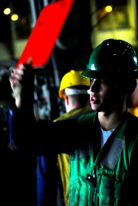 US Navy 080109-N-7526R-159 Seaman Victor Ledesma signals to the Military Sealift Command ammunition ship USNS Flint (T-AE 32) during a connected replenishment