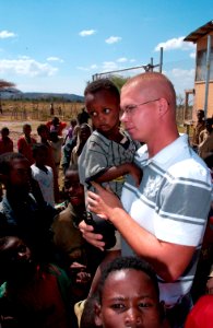 US Navy 080117-F-4089F-037 Builder 2nd Class Ryan Woolridge stands with children of the Bilate Charicho region of Ethiopia as they wait to attend the dedication of two new school buildings